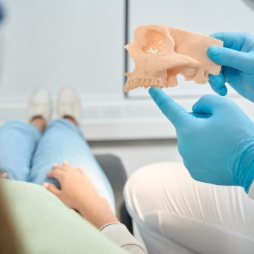 Un dentiste montre à son patient un modèle de mâchoire pour montrer la perte osseuse