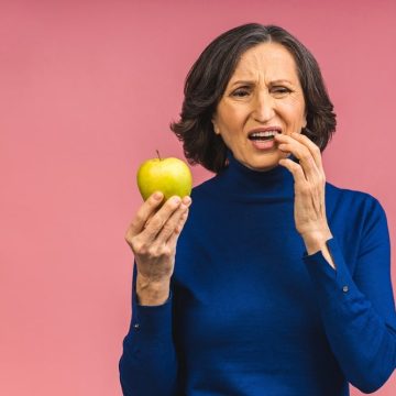 Une femme a une douleur dentaire en mangeant