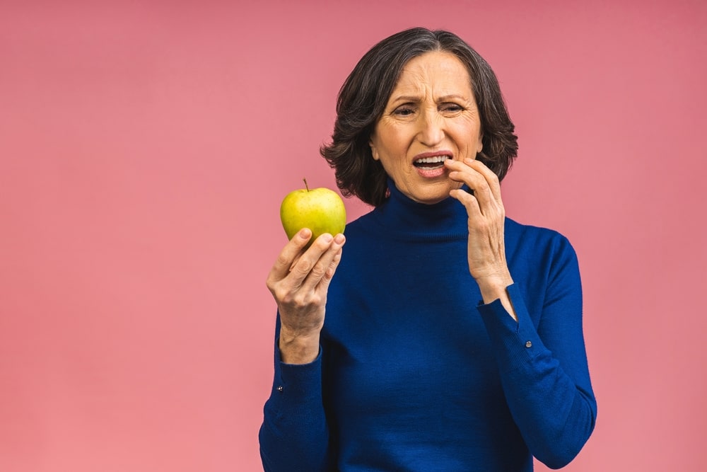 Une femme a une douleur dentaire en mangeant